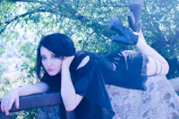 a young woman laying on a rock in a black dress