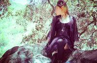 a woman in a black dress sitting on a rock